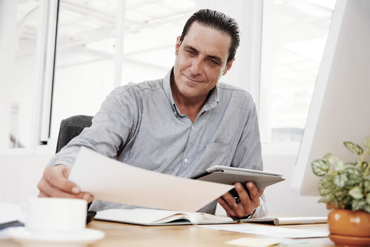 Mãos conferindo as cláusulas de um contrato sobre a mesa do escritório