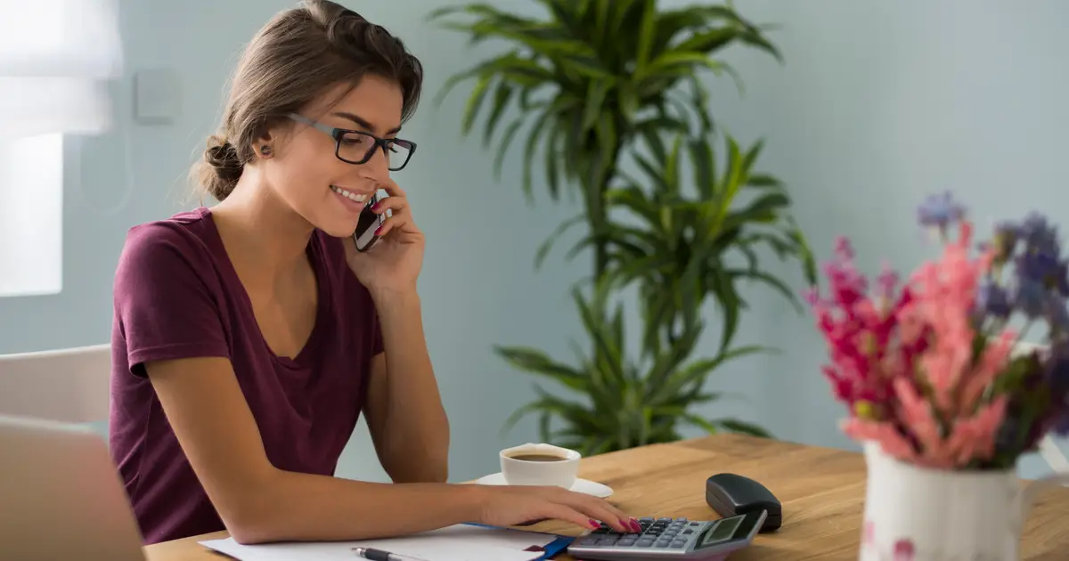 Mesa de trabalho com calculadora, papéis e anotações de contas